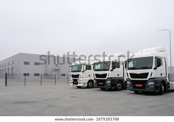 Trucks stand in a row at a truck\
stop. Cargo semi-trailers for delivery and loading of cargo,\
logistics, cargo transportation. Car service and truck\
maintenance.