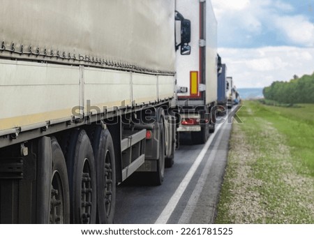 Trucks are stuck in traffic. A column of semi-trailers on the freeway. Concept of disruption in transportation logistics and supply chains