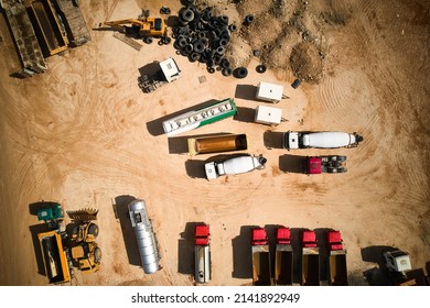 Trucks and tippers parked at open pit sand mining. Top down aerial view of different dump trucks at construction site