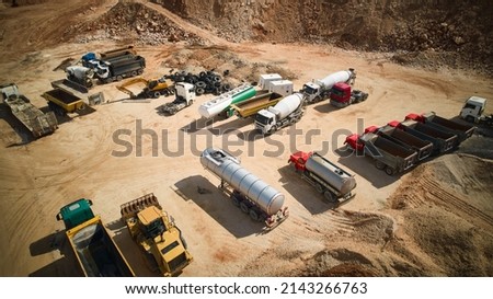 Trucks and tippers parked at open pit sand mining. Aerial view of different dump trucks at construction site