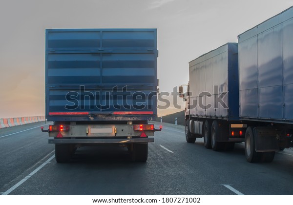 Trucks\
with trailers move along the highway at\
sunset