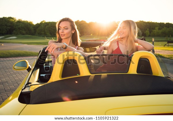 True friends are like\
diamonds! Close up portrait of two young attractive good-looking\
girls sincerely smiling, while relaxing in the cabriolet in summer.\
 