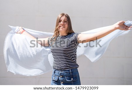 True happiness concept. Young blond caucasian woman in casual clothes turning around and laughing outside in a sunny suummer day over grey solid background