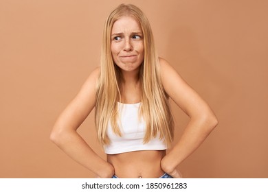 True Human Emotions. Studio Shot Of Frustrated Young Blonde Woman With Piercing And Freckles Looking Away Making Grimace, Feeling Uncomfortable Because Of Awkward Silence, Does Not Know What To Say