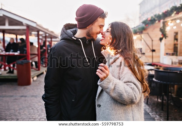 True love emotions of joyful cute couple enjoying
time together outdoor in city. Lovely happy moments, having fun,
smiling, christmas time falling in love  with sparklers on the
background of the city