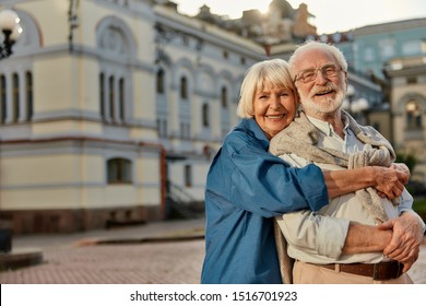 True Love Has No Expiration Date. Portrait Of Cheerful Senior Couple In Casual Clothing Embracing Each Other And Looking At Camera With Smile While Standing Together Outdoors