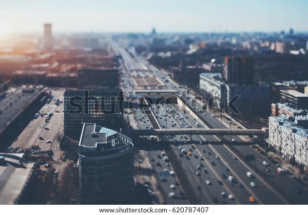 True tilt shift shooting of highway in\
metropolis from high point: multiple residential and office\
buildings, parking, many cars on busy streets of the city,\
crosstown traffic, sunny\
springtime