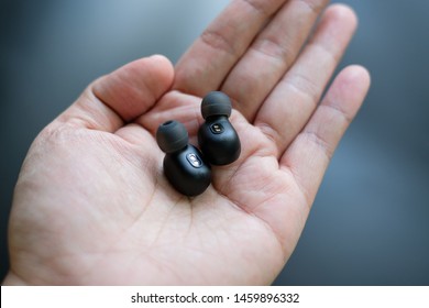 True Wireless in-ear headphones in hand.