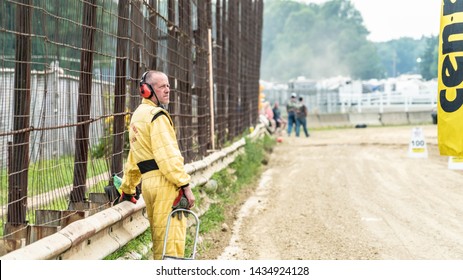 Trumbull County, Ohio/USA - September 9, 2018: Caucasian Male In Bright Yellow Jump Suit And Ear Protectors Stairs Off Into Distance Standing Next To Dirt Road.