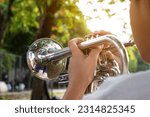 Trumpet instrument holding in hands of Asian student who is practising before playing it at a ceremony to honor the national flag in the morning. Soft and selective focus on circle bell of trumpet.