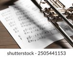 Trumpet and music sheet papers with notes on wooden table, closeup