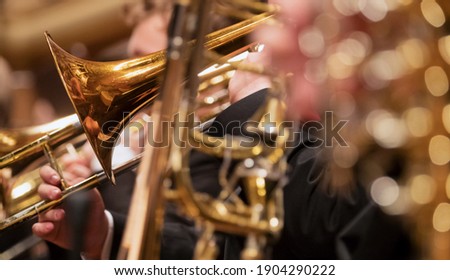 Trumpet professional player with symphony orchestra performing in concert on background.