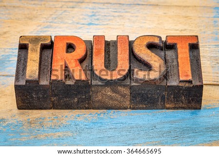 trust word banner  - text abstract  in vintage letterpress wood type blocks stained by color inks against grunge painted wood
