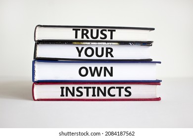 Trust your own instincts symbol. Books with words 'Trust your own instincts'. Beautiful white background. Businessman hand. Copy space. Business and trust your own instincts concept.