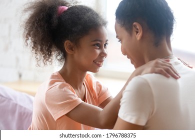 Trusting relations. Affectionate loving black mommy or elder sister and school age girl hugging and looking in eyes of one another, african mom and preteen daughter enjoying happy moments together - Shutterstock ID 1796788375