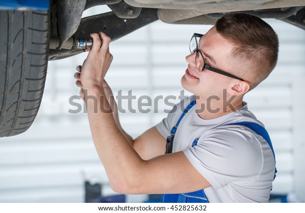 Trustworthy pro.\
Shot of a professional car mechanic checking a car undercarriage\
working with a wrench\
