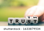 Truth instead of trust. Hand turns dice and changes the word "Trust" to "Truth".