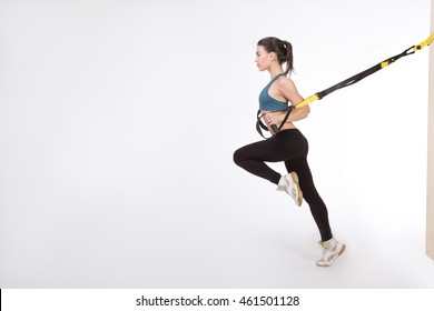 TRX concept. Beautiful lady exercising her muscles with help of suspension trainer sling or suspension straps isolated on white background.