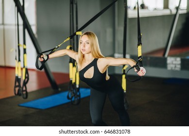 TRX Concept. Beautiful Lady Exercising Her Muscles. Athletic Shirtless Female Doing Workouts On A Back With Power Exercise Machine In A Gym Club.