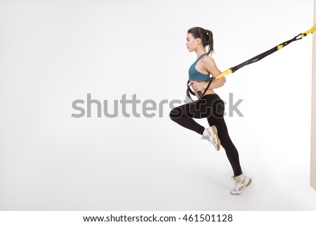 TRX concept. Beautiful lady exercising her muscles with help of suspension trainer sling or suspension straps isolated on white background.