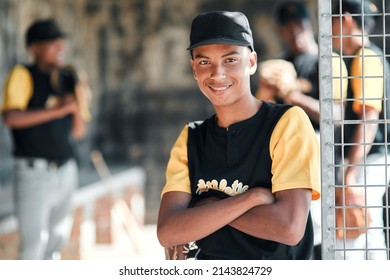 I Try To Be The Best For My Team. Portrait Of A Young Baseball Player Standing With His Arms Crossed With His Teammates Standing In The Background.