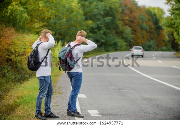 Try to stop some car. Travel and transport\
concept. Twins men at edge of road nature background. Reason people\
pick up hitchhikers. Missed their bus. Need help. Cheap transport.\
Transport problem.