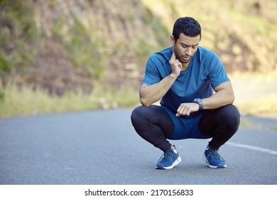 Trying To Bring My Heart Rate Back Down. Full Length Shot Of A Handsome Young Man Crouching And Timing His Pulse During His Outdoor Workout.