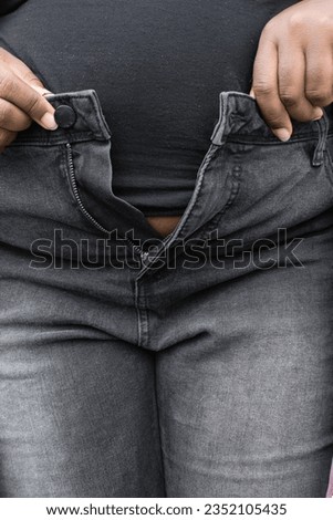 Trying to button jeans that are too small, fat woman trying on too small jeans, clothes will not fit plussize woman, woman with a fupa trying to fit in jeans
