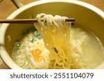 Trying to eat instant ramen noodles cooked in a pot with chopsticks.