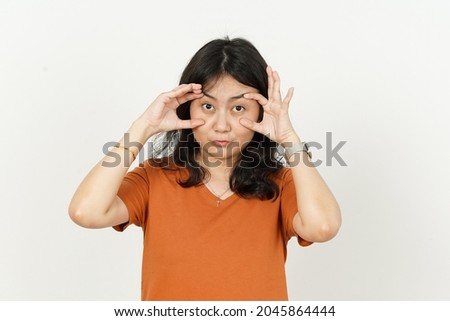 Trying open the eyes of beautiful asian woman Wearing orange T-shirt isolated on white background