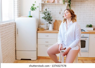 Trying to relax. Nice young woman sitting on the stool in the kitchen while trying to relax with a cup of tea - Shutterstock ID 1374327578