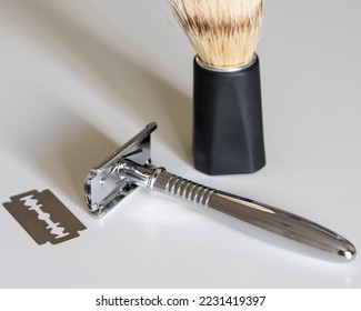 T-shaped metal chrome razor with replaceable blades. A safety razor whose blade is inserted inside and clamped on both sides on a t-shaped razor. White background and minimalism