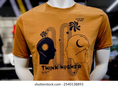 T-shirt with a message - Think Higher - on a mannequin at a clothing store, a close up view with bokeh background. - Powered by Shutterstock