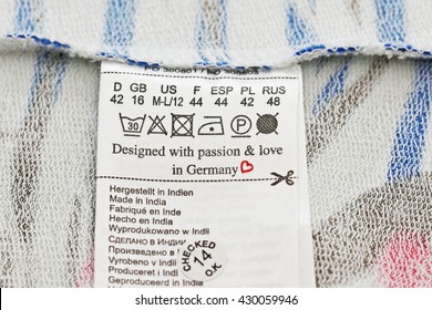 T-shirt Wrong Side Fabric Background, Washing Multilingual Label, Text Designed With Passion&love In Germany, Made In India, Size In Several Languages, Icon Iron, Scissors, Heart, Dry Cleaning, Drying