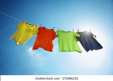 T-shirts hanging on a clothesline in front of blue sky and sun