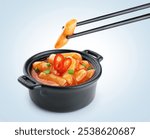 Tteokbokki rice cakes with chilli sauce and onion. Korean cuisine dish. Chopsticks hold tteokbokki rice cakes.