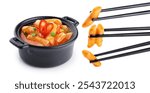 Tteokbokki rice cakes with chilli sauce and onion isolated on white background. Korean cuisine dish. Chopsticks hold tteokbokki rice cakes.