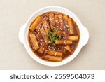 Tteokbokki or Topokki , stir fried rice cake stick, popular Korean street food with spicy gochujang sauce and sesame seed. 
