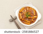 Tteokbokki or Topokki, stir fried rice cake stick, popular Korean street food with spicy gochujang sauce and sesame seed. 
