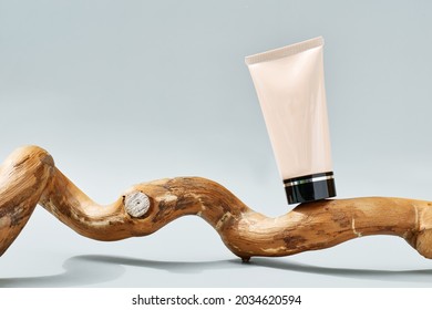 Tube of BB or CC cream on wooden snag on pastel gray background. Presentation stage for cosmetic product advertising. Eco-bio cosmetics concept. Beauty product promotion trendy minimalist mockup.