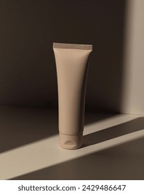 Tube of cosmetic cream. Front view, Beige cream bottle and natural shadow light from the sun on beige background.  Mock up, close-up photo. Background shadow, skin care product. Face cream. Cream tube