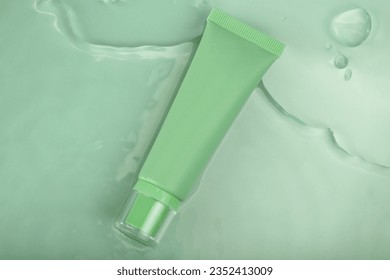 Tube cream cosmetic in clean transparent water with sunlight on green background, flat lay, top view, water surface - Shutterstock ID 2352413009