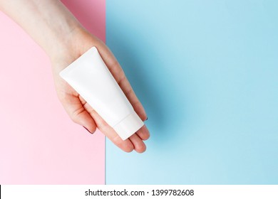 Tube With Cream In Female Hand, Blue And Pink Background, Top View, Cosmetics Care Concept