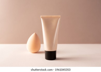 Tube Tonal Foundation Makeup Mockup And Cosmetic Beauty Blender Sponge On Beige Background. BB Or CC Cream Container For Branding