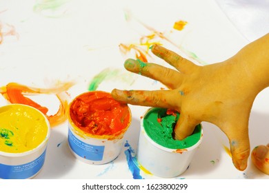 Tubes With Colorful Bright Colors And Text: Gel Finger Paints, With Baby's Fingers Stuck Inside. Selective Focus. Concept Of Children's Fun.