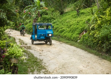 Tubigon, Bohol, Philippines - Nov 2021: A tricycle passes through a dirt road made of crushed limestone, known locally as anapog.
