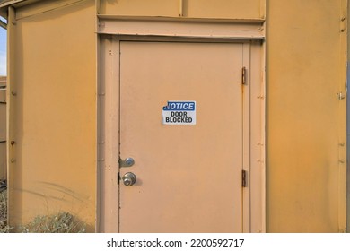 Tucson, Arizona- Notice Door Blocked Signage On A Cream Colored Door. Slightly Peeled Sign On A Blocked Door Outside A Painted Yellow Utility Infrastructure.