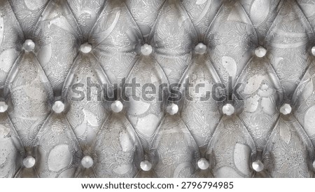 Tufted silver leather texture background with elegant floral pattern engravings and metallic buttons upholstery