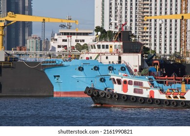 Tug Boat Passing Cargo Ship In Front Of Floating Dry Dock In Chao Phraya River. Bangkok, Thailand.