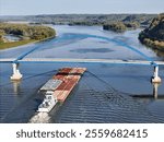 Tug boat pushing a set liquid tank cargo barges up the Mississipppi river traveling under the Dale Gardner Veterans Memorial Bridge at Savanna illinois 